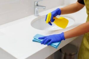Person cleaning bathroom vanity at vacation rental property
